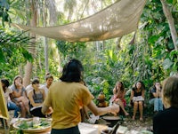 a group of people sitting around a table in the jungle